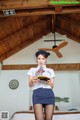 A woman in a white shirt and blue skirt holding a plate of food.