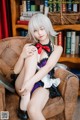 A woman sitting on a chair in front of a book shelf.