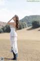 A woman in a white dress standing in a field.