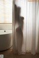 A shadow of a person standing in front of a white curtain.