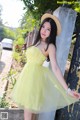 A woman in a yellow dress and straw hat posing for a picture.