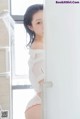 A woman in a white shirt and red panties standing in a shower.