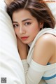 A woman laying on top of a bed next to a pillow.