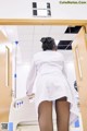 A woman in a white lab coat is standing in a hospital room.