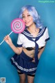 A woman in a sailor outfit holding a lollipop.