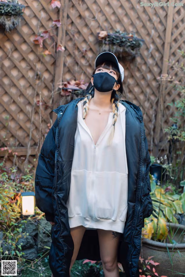 A woman wearing a black face mask standing in a garden.
