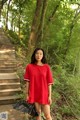 A woman in a red dress standing on a set of stairs.